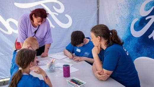 Two volunteers helping a group of children to draw