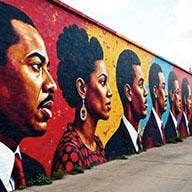 Profiles of six Black persons looking to the left, painted on the outside wall of building.