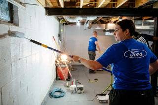 Female wearing Ford T-shirt painting a basement wall.