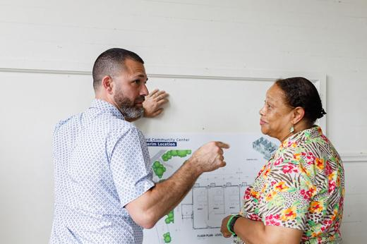 Hassan Hammoud, Senior Manager of Essential Services for Ford Philanthropy and Dr. Clarice White, project champion and Stanton School alumna, discuss with plans for the Ford Community Center on the wall between them.
