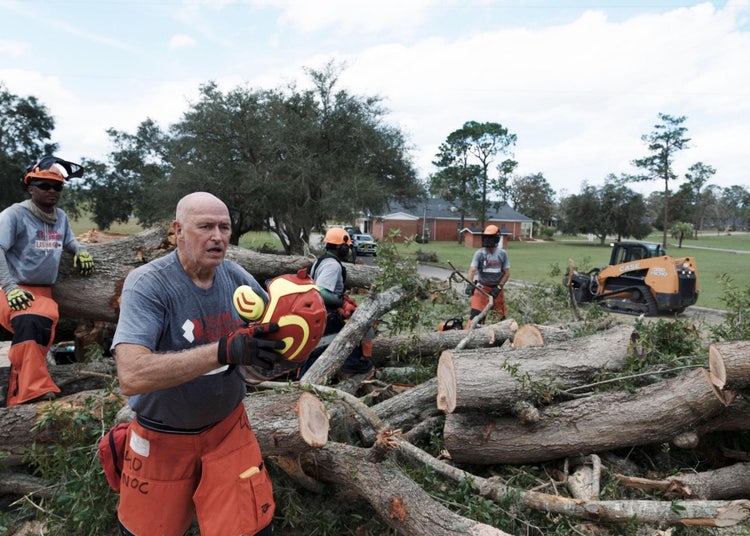 Team Rubicon volunteers carrying large branches out of a backyard