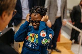 African American child squints while adjusting eyeglasses.