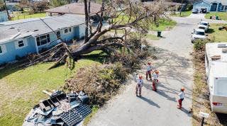Overhead shot of tree damage on a home with Team Rubicon volunteers in the street