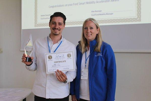 Winner holding an award next to a person