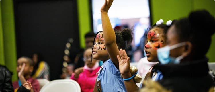 A girl raising a hand in the middle of a group
