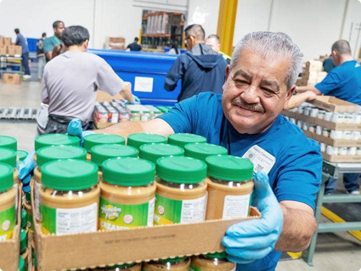 A man moving a box full of plastic cans