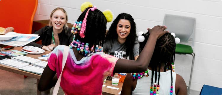 Two women sitting on a table and two girls in front of them