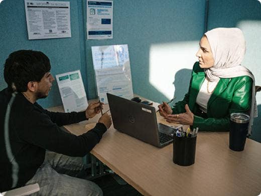 A woman from an office sitting at her desk talking to another person