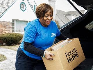 A woman taking a box of donations out of a trunk