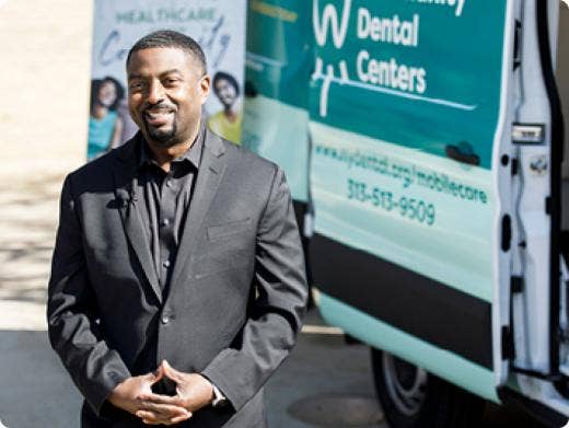 A man standing next to a mobile dental center