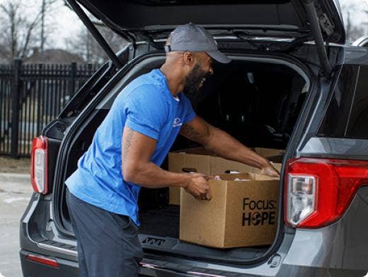 A man putting a donation box in the trunk of a car